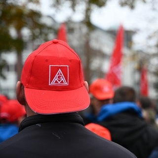 Der Kopf eines Mannes von hinten. Er trägt eine rote Basecap mit dem Logo von "IG Metall". Die Gewerkschaften und die Arbeitgeber haben sich nun auch in Rheinland-Pfalz auf einen Tarifabschluss geeinigt.