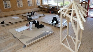 Zimmerleute arbeiten an technischen Zeichnungen.
