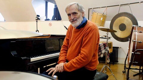 Helmut Lachenmann am Klavier und mit weiteren Instrumenten im Hintergrund. 