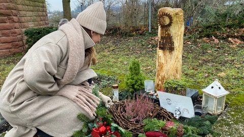 Nicole auf dem Friedhof, am Grab ihres verstorbenen Manns.