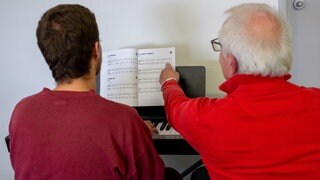 Musiker Bernd Oster (r) lehrt Häftling Vlady in der Justizvollzugsanstalt (JVA) Wittlich das Klavierspielen.