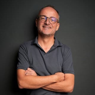 Zukunftsforscher Harry Gatterer schaut direkt in die Kamera und lacht. | Zukunftsforscher Harry Gatterer: Was die Zukunft bringt 