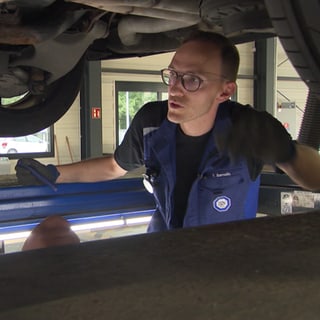 TÜV-Prüfer spricht mit einem Fahrzeugbesitzer