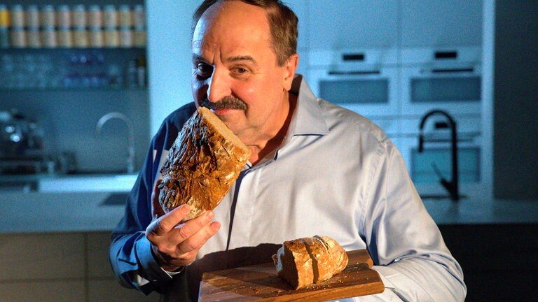 Johann Lafer mit seinem selbstgebackenen Bauernbrot, er schnuppert an dessen knuspriger Kruste.