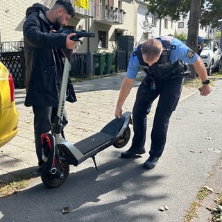 Ein Polizist kontrolliert im Rahmen der E-Scooter-Kontrollwoche den Roller eines Mannes in Mainz
