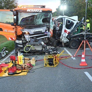 Unfall mit zwei Schwerveretzten. Einsatzkräfte stehen nach einem Unfall neben zwei beschädigten Fahrzeugen. 
