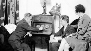Zwei Männer und eine Frau hören Radio, Deutschland, 1920er. Gespräche waren 1930 eine ganz neue Form im Radio