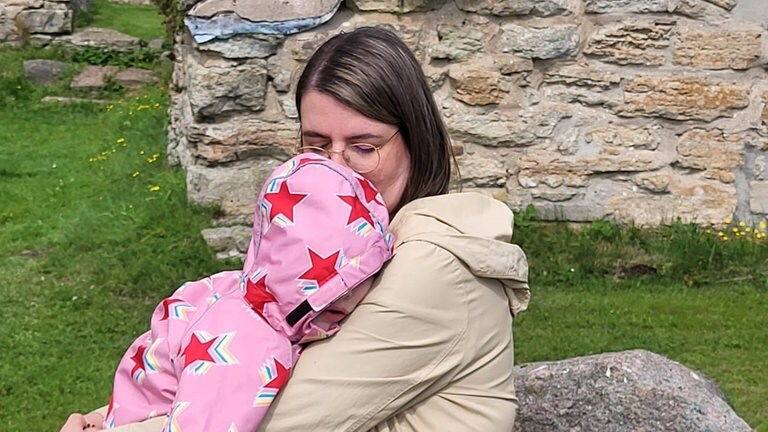 Junge Frau umarmt beim Spazieren ihre Tochter.