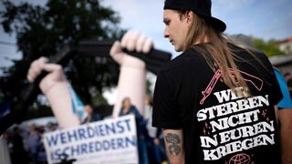  Demonstrant mit T-Shirt "Wir Sterben Nicht in Euren Kriegen" bei einer Kundgebung von Wehrdienst-Gegnern und Friedensbewegung im August 2025 vor dem Verteidigungsministerium.