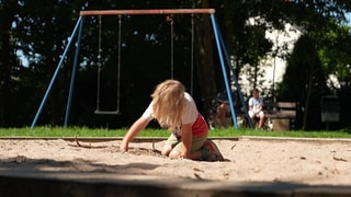 Ein Kind spielt auf einem Spielplatz im Sand. Dieser Spielplatz soll nach Angaben der Gemeinde Weissach im Tal Bauplätzen weichen.