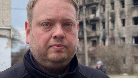 Tobias Schneider steht vor Trümmern in Isjum.
