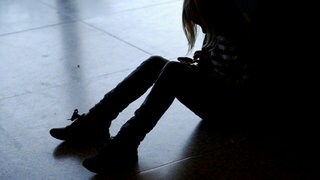 Ein kleines Mädchen sitzt mit gesenktem Kopf allein auf dem Fußboden. Wegen Corona haben viele Kinder psychische Probleme.