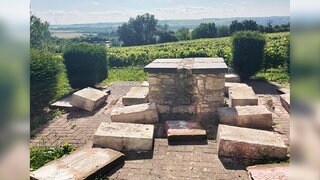 Nur der Stein-Tisch ist noch übrig von der Sitzgelegenheit im Weinberg. Rund um den Tisch liegen herausgebrochene Steinplatten, die ursprünglich mal Sitzbänke darstellten.