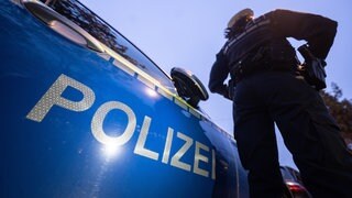 Ein Polizist nehmen einem Einsatzwagen (Symbolbild). In Lauffen hat ein 18-Jähriger seinen Vater mit einem Messer angegriffen.