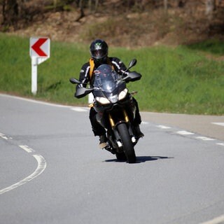 Sportlicher Motorradfahrer auf einer Landstraße.