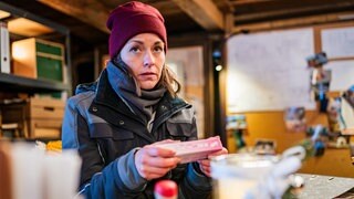 Sophie (Janina Flieger) sitzt in ihrem Büro und hat einen Schwangerschaftstest in der Hand