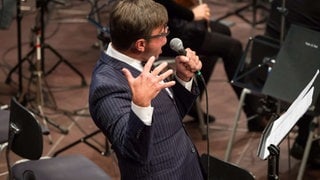 Mann mit Anzug singt ins Mikrophon