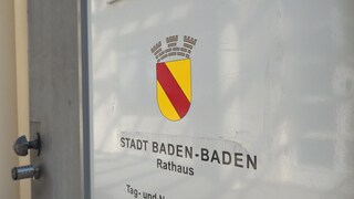 Eine Tür im Rathaus mit dem Wappen der Stadt Baden-Baden. Der Gemeinderat der Stadt hat die Abstimmung zu den Sparmaßnahmen vertagt.
