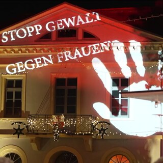 'Stopp Gewalt gegen Frauen' an eine Hauswand projiziert