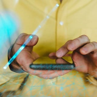 Hände halten ein Smartphone - Lichtreflexe zeigen, dass das Handy gerade mit mobilen Daten genutzt wird.