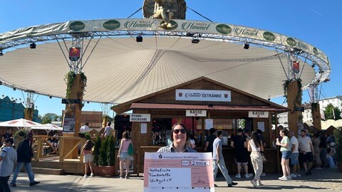 Anne Bürckel hält einen Scheck in Höhe von 2.500 Euro für die katholische Familienpflege e.V. in den Händen. Die Spende kommt von Harald Hegebarth, Inhaber des Wasenhimmels.