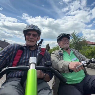 Zwei Männer fahren mit einer Rikscha durch einen Ort.