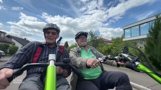 Zwei Männer fahren mit einer Rikscha durch einen Ort.