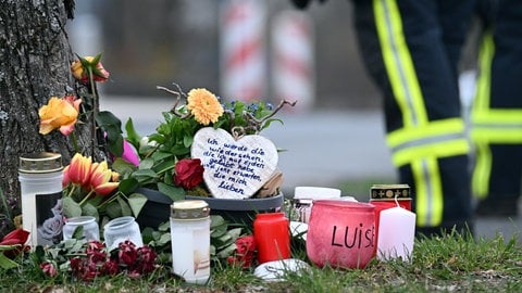 Auf der Straße stehen Blumen und Lichter, um an die 12-jährige Luise aus Freudenberg zu erinnern, die 2023 getötet wurde. Ihr Fall wird nun in einem Zivilprozess verhandelt.