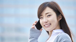 Junge japanische Geschäftsfrau mit Smartphone lächelt: Bei der Gleichberechtigung gehört Japan zu den rückständigsten Staaten. Doch Japanerinnen wehren sich mit wachsendem Erfolg gegen das tief verankerte Rollenbild der dienenden und dekorativen Frau.