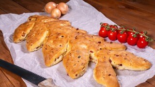 Brot aus Dinkel mit Speck und Zwiebeln: Das knusprig gebackene Brot liegt mit Cocktailtomaten garniert bereit.