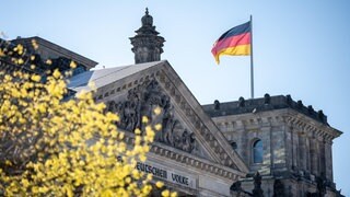 Deutsche Flagge weht am Reichstagsgebäude. Politologe Christian Stecker fordert ein Umdenken in den Parlamenten. Mit Brandmauern sollte die Politik konstruktiver umgehen, sich die Mehrheiten für Vorhaben flexibel und an den Sachthemen orientiert holen. Was genau er damit meint, das besprechen wir mit dem Politikwissenschaftler Christian Stecker in SWR1 Leute.