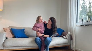 Noemi mit ihrer Mutter auf dem Sofa: Die Neunjährige kann derzeit nicht zur Schule, weil die Stadt Stuttgart den Vertrag mit dem Träger für die Eingliederungshilfe gekündigt hat.