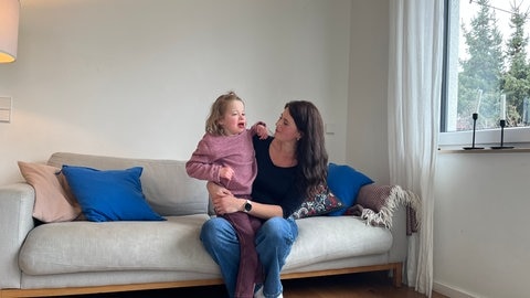 Noemi mit ihrer Mutter auf dem Sofa: Die Neunjährige kann derzeit nicht zur Schule, weil die Stadt Stuttgart den Vertrag mit dem Träger für die Eingliederungshilfe gekündigt hat.