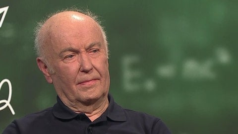 Mit 81 Jahren arbeitet Volker Hoffmann noch als Lehrer und unterrichtet unter anderem Mathe und Physik. Im Hintergrund ist eine Schultafel zu sehen.
