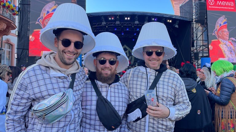 Weiberfastnacht auf dem Mainzer Schillerplatz: Drei Männer haben sich als Lampe verkleidet, mit Lampenschirmen auf dem Kopf. 