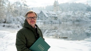 Trauer-Redner Markus steht mit seiner Rednermappe am verschneiten Stadtsee von Bad Waldsee