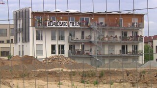 Ein Haus mit einem Banner mit der Aufschrift: "Bezahlbare Mieten". Die Sozialquote für Wohnungsmieten ist Thema im Mannheimer Gemeinderat
