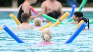 Bei einer Schwimmstunde lernen Kinder Schwimmen mit einer Schwimmnudel.