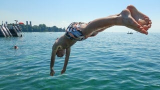 Sprung ins kühle Nass: Ein junger Mann macht vor Friedrichshafen einen Köpfler in den Bodensee. Der Hitzesommer 2026 hat vielen Strand- und Freibädern kräftige Besucherzuwächse beschert.