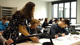 Lehrerin steht zwischen Schülern einer Schulklasse der Oscar-Paret-Schule