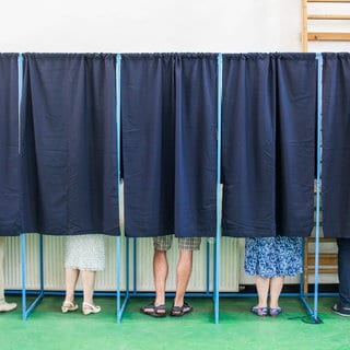  Menschen in Wahlkabinen - wie ist die Psychologie der Wahlentscheidung und macht es Sinn, taktisch zu wählen?