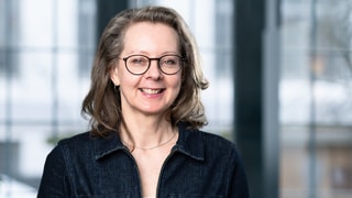 Finanzcoachin Dani Parthum schaut in die Kamera und lächelt.