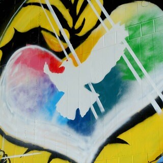 Graffiti mit weißer Friedenstaube in einem farbigen Herzen: Während der Friedensbewegung der 1980er- und 1990er-Jahre galt der Pazifismus als respektable politisch-ethische Haltung. Das hat sich mit dem russischen Angriffskrieg gegen die Ukraine geändert. 
