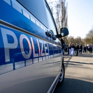 Ein Polizeiauto steht vor einer Menschengruppe (Symbolbild): Die 16-jährige Schülerin, die in Ludwigshafen im Unterricht starb, starb eines natürlichen Todes, so die Staatsanwaltschaft.