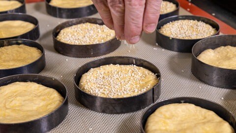 Rezept Burgerbrötchen selber machen: Den Teig mit Sesam bestreuen.