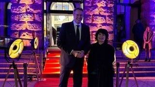 Die Autorin Monika Helfer, die mit der Zuckmayer-Medaille ausgezeichnet wird, und RLP-Ministerpräsident Alexander Schweitzer (SPD) auf dem roten Teppich