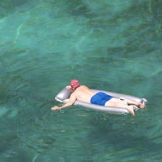 Ein Mann genießt das Meer in seiner aufblasbaren Matratze am Strand von Cala Pi auf Mallorca. Bei sommerlichen Temperaturen waren an diesem Wochenende einige Stände sehr voll. 