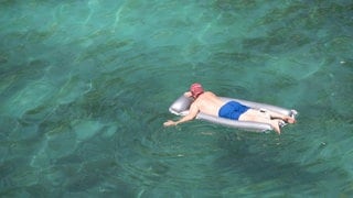 Ein Mann genießt das Meer in seiner aufblasbaren Matratze am Strand von Cala Pi auf Mallorca. Bei sommerlichen Temperaturen waren an diesem Wochenende einige Stände sehr voll. 