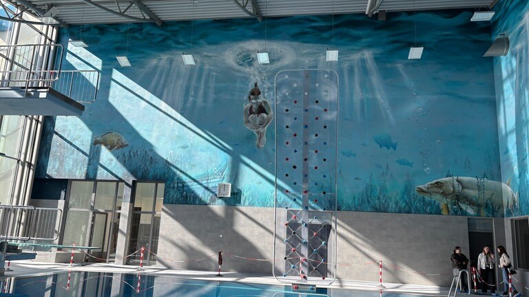 Ein Graffiti am Sprungbecken im Taubertsbergbad zeigt eine Frau beim Sprung mit angezogenen Beinen.