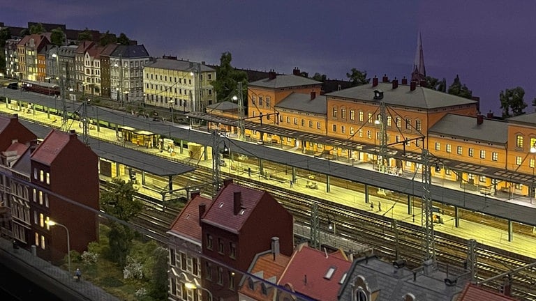 Der Bahnhof Bremburg bei Nacht. Die Reisenden warten auf den Zug nach … Lassen Sie ihrer Fantasie freien Lauf.